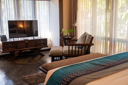 a hotel room with a tv and a bed and chairs at Sibsan Resort & Spa Maetaeng Chiang Mai in Mae Taeng