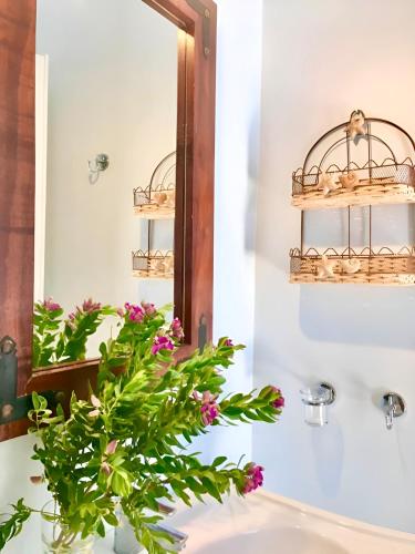 a bathroom with a mirror and a sink with flowers at Mykonos Dot - The Villas in Mikonos