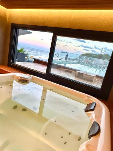a bath tub in front of a window with a view of the ocean at BALUARTE POUSADA in Torres