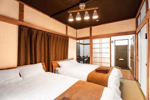 a hotel room with two beds and a window at 川越古民家Takezo in Kawagoe