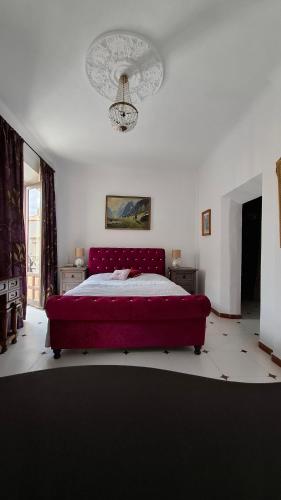 a bedroom with a red bed and a chandelier at Casa Antik in Loja