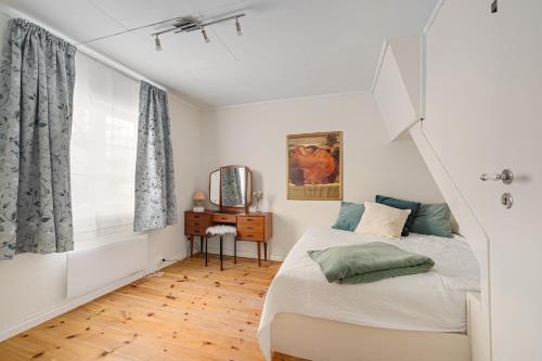 a bedroom with a bed and a desk and a window at Hovedhuset in Kragerø