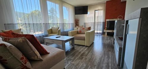 a living room with a couch and chairs and a tv at Апартамент При Рени in Koprivshtitsa