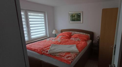 a bedroom with a bed with red sheets and a window at Zum Rosengarten in Rambin