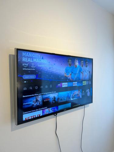 a flat screen tv hanging on a wall at Room with private bathroom 5 min to Legoland & Windsor Castle - free parking and EV plug in Windsor