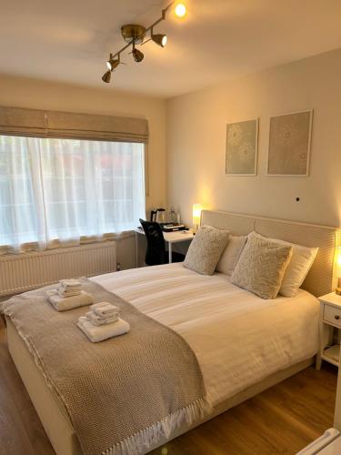 a bedroom with a large bed with two towels on it at Room with private bathroom 5 min to Legoland & Windsor Castle - free parking and EV plug in Windsor