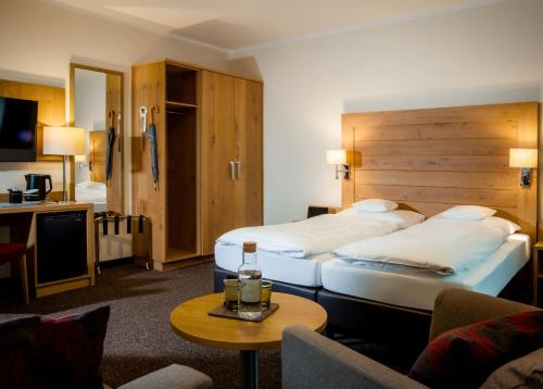 a hotel room with two beds and a table at Euler Neuschönau - 4 Sterne Superior Hotel in Neuschönau