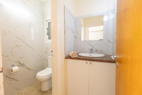 a bathroom with a toilet and a sink and a mirror at Papaya Royal Villa in Ayia Napa