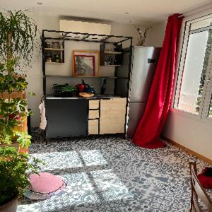 a kitchen with a refrigerator and a red curtain at À l'ombre du mûrier in Blauvac