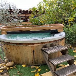 a wooden hot tub with two benches in the grass at À l'ombre du mûrier in Blauvac