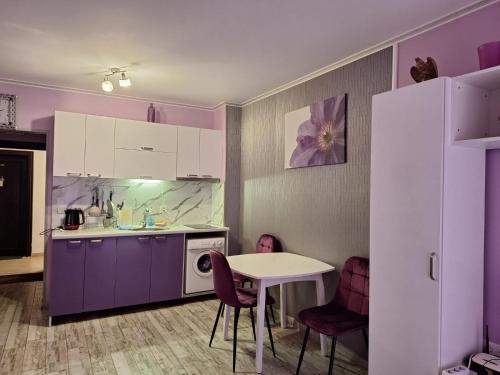 Parus 4 Studio في بوموري: مطبخ بخزائن أرجوانية اللون وطاولة وكراسي