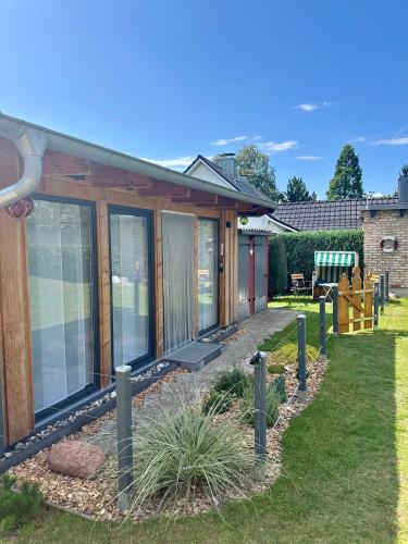 a house with glass doors and plants in the yard at Windrose in Korswandt