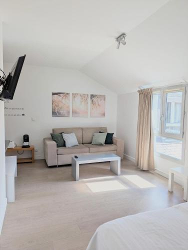 a white living room with a couch and a table at Studio détente proche Sanctuaires in Lourdes