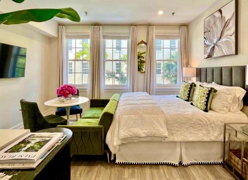 a bedroom with a bed and a couch and windows at The Green Room - Pool View with Parking Spot at 1920s Historic Residence with 24x7 Reception Desk on Palm Beach Island in Palm Beach