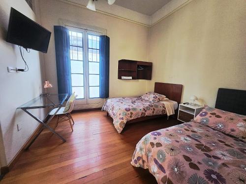 a room with two beds and a desk and a window at Santa Marta Casona in Arequipa