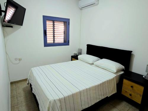 a bedroom with a bed with white sheets and a window at Next to the marina in Ashkelon