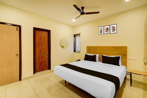 a bedroom with a large bed with a ceiling fan at Super Hotel O Nivara in Hyderabad
