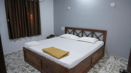 a bedroom with a bed with a yellow blanket on it at Hotel Akshada & Guest House in Banda