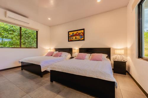 two beds in a bedroom with two windows at Amazilia Guesthouse in Liberia