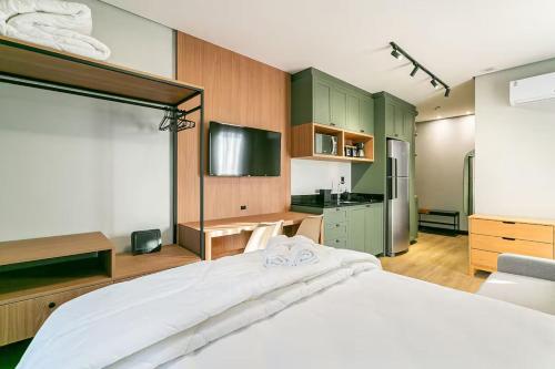 a bedroom with a large white bed and a kitchen at Loft Completo com Piscina Aquecida 250m da Vila Germânica in Blumenau