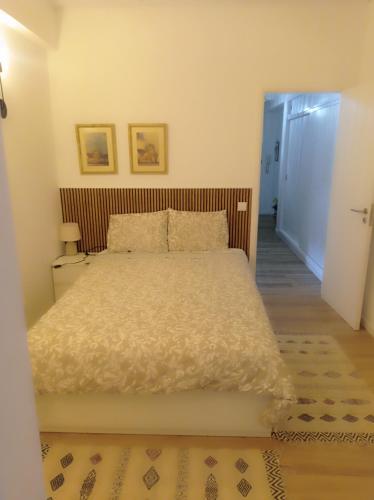 a bedroom with a white bed with a wooden headboard at Beach Blue Sesimbra in Sesimbra