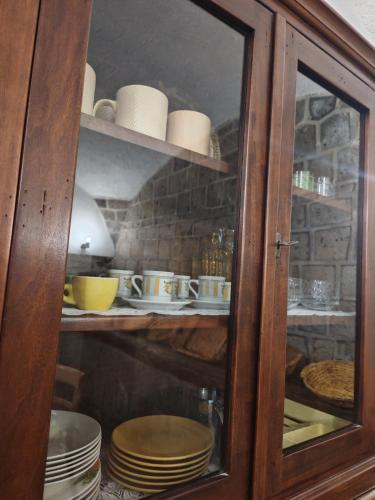 a glass cabinet with plates and dishes in it at Gli Ulivi del Nonno - Casale immerso nel verde a pochi chilometri dalla Reggia - in Caserta