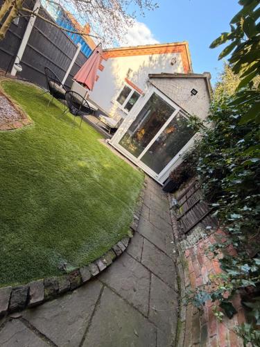 a backyard with a lawn and a house with a window at Cozy Cottage Coventry self check-in after 3pm, Pets Friendly in Longford