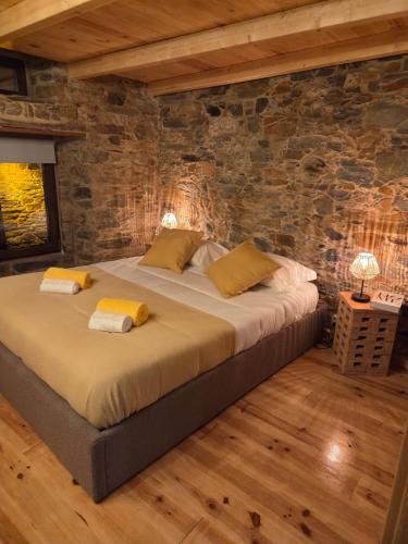 a bedroom with a large bed in a stone wall at Casa do Tear in Sobreira Formosa