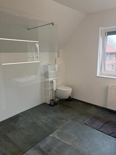 a white bathroom with a shower and a toilet at Ferienhaus Emilius in Butjadingen