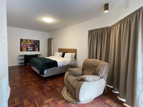 a bedroom with a bed and a chair and a couch at The Wild Side in Sandton