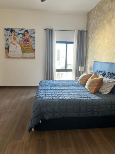 a bedroom with a blue bed and a painting on the wall at Loteria Mexicana in Senecú
