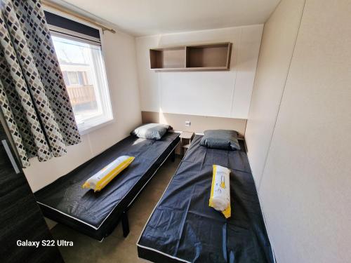 two beds in a small room with a window at Valras Jasmin 68 in Sérignan