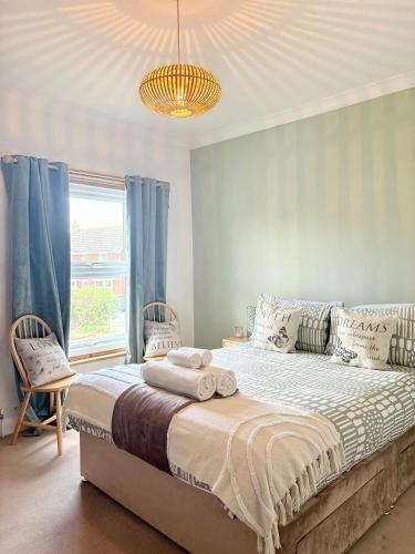 a bedroom with a bed with blue curtains and a window at Beach Walk Cottage in Walton-on-the-Naze