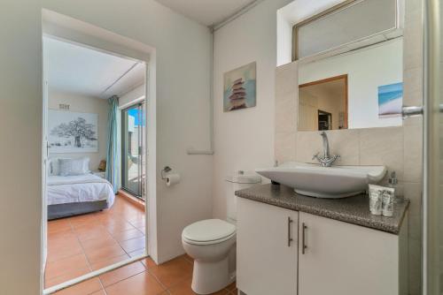 a bathroom with a sink and a toilet and a bedroom at Seaview in Hout Bay
