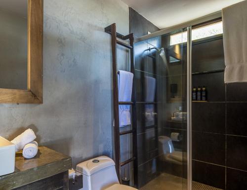 a bathroom with a toilet and a glass shower at 99 Surf Lodge in El Limón