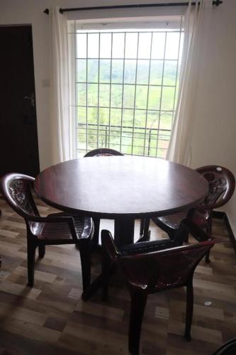 a wooden table and chairs in a room with a window at Rakas Guest House Ooty in Ketti