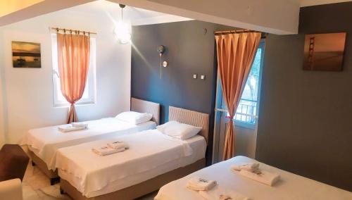 two beds in a room with orange curtains at Haluk Otel in Oren
