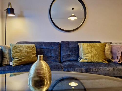 a living room with a blue couch and a mirror at Stylish Spacious Serviced Apartment next to City Centre with Free Parking - Contractors & Relocators in Coventry
