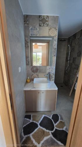 a bathroom with a sink and a mirror and a rug at Semelia & Maria's Guest Houses - Cozy Stay for 2 in Spata