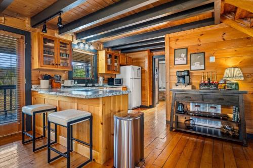 a kitchen with wooden walls and wooden flooring at Bearfoot Pines - True Log Cabin - Wi-Fi, Hot Tub, Fishing, Deck with views! - Mins to PF in Sevierville