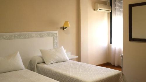 a hotel room with two beds and a window at Hotel Recio in Santa Olalla de Toledo