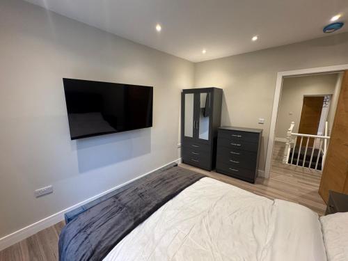 a bedroom with a bed and a flat screen tv on the wall at Brand New Luxury Centrally Located 2BR Apartment in Horninglow