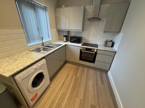 a kitchen with a washing machine and a sink at Brand New Luxury Centrally Located 2BR Apartment in Horninglow