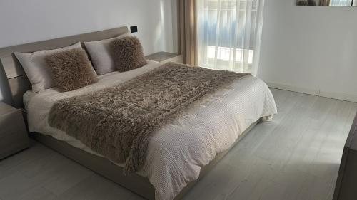 a bedroom with a large bed with a brown blanket at Hij Apartaments in Rădăuţi