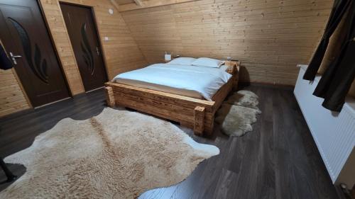 a bedroom with a bed and two rugs at Old Chalet Apuseni in Arada
