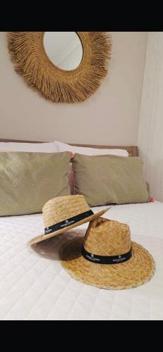two straw hats and a mirror on a bed at Vivenda Oliveira - Alojamento Local in Lamego