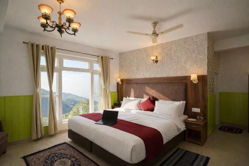 a bedroom with a large bed with a large window at Great Himalayan Resort in Dharmsāla