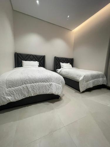 two beds in a room with white walls at شقة مفروشة in Al Khobar