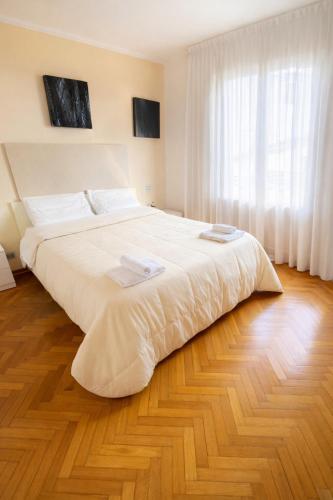 a large white bed in a bedroom with a wooden floor at Joe's apartments in Carrara