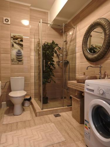 a bathroom with a toilet and a shower and a washing machine at SeaLaVie - Summerland Mamaia in Mamaia